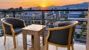 A balcony with two chairs and a small table, overlooking a cityscape during sunset. - Nile View Hotels - Quara  (Gondar)