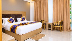 A hotel room with a large bed, a wooden headboard, two chairs, a small table, and a view of greenery outside. - Nile View Hotels - Quara  (Gondar)