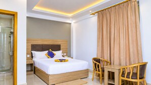A modern hotel room with a bed, bedside table, chairs, and a shower area. - Nile View Hotels - Quara  (Gondar)