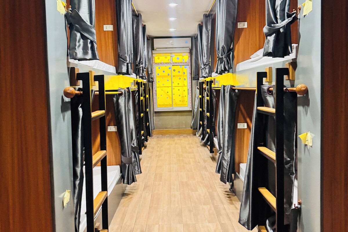 A corridor with bunk beds, wooden walls, and a tiled floor.