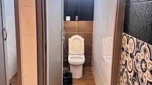 Ein schmales Badezimmer mit Toilette, Dusche und Fenster.