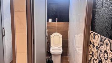 Un bagno stretto con il water, una doccia e una finestra.