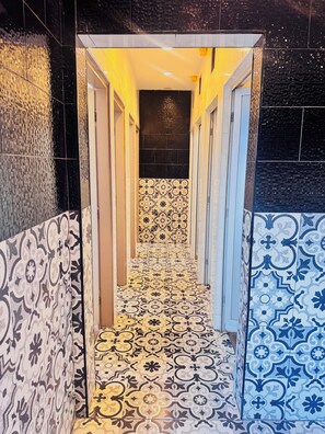 A narrow hallway with patterned tiles on the walls and floor, leading to a dark room. - Lao Smart Box Hostel (Vientiane)