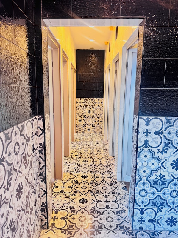 Un pasillo estrecho con baldosas estampadas en las paredes y el suelo, que conduce a una habitación oscura.