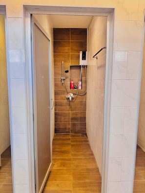 A narrow hallway leading to a shower area with a wooden wall, a tiled floor, and a control panel on the wall. - Lao Smart Box Hostel (Vientiane)