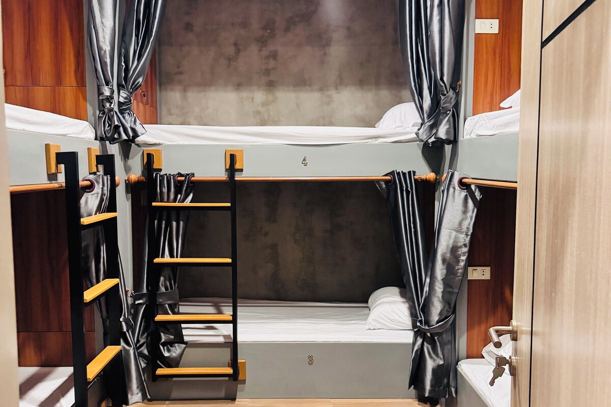 A compact room with bunk beds, a wooden ladder, and a small sink.