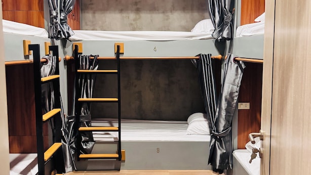 Ein kleines Zimmer mit Etagenbetten, einer Holzleiter und einem kleinen Waschbecken.