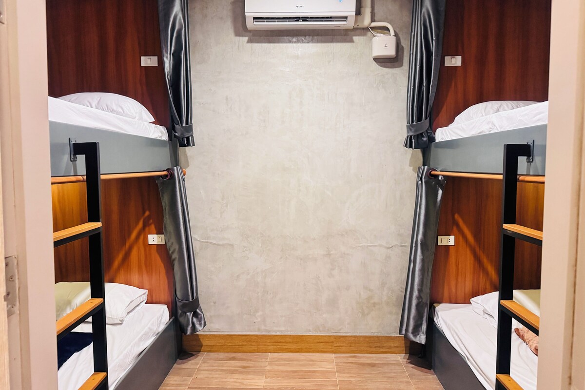 A room with two bunk beds, an air conditioning unit, and a curtain.