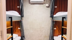 Ein Zimmer mit zwei Etagenbetten, einer Klimaanlage und einem Vorhang.