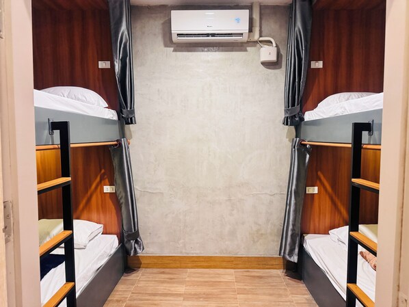 Quarto com duas camas beliche, ar condicionado e cortina.