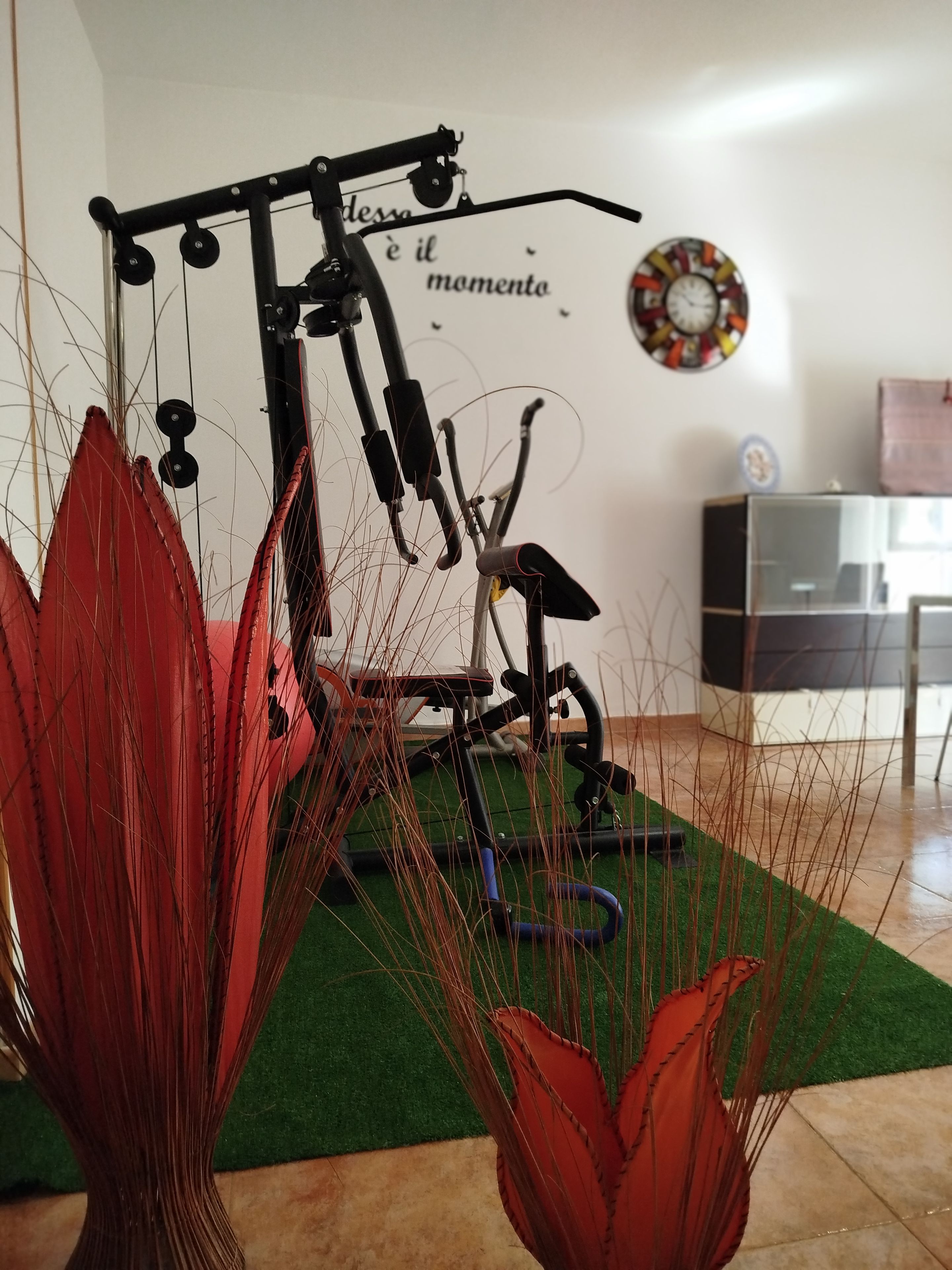 Une pièce comprenant un vélo d’appartement, une horloge murale et un petit meuble de rangement.