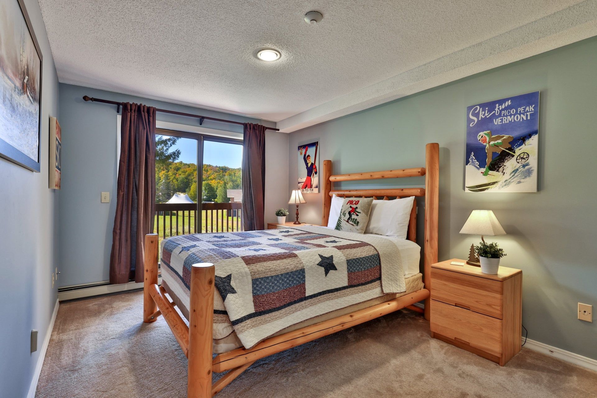 A bedroom with a wooden bed, a nightstand, a lamp, a window with curtains, and a poster on the wall.