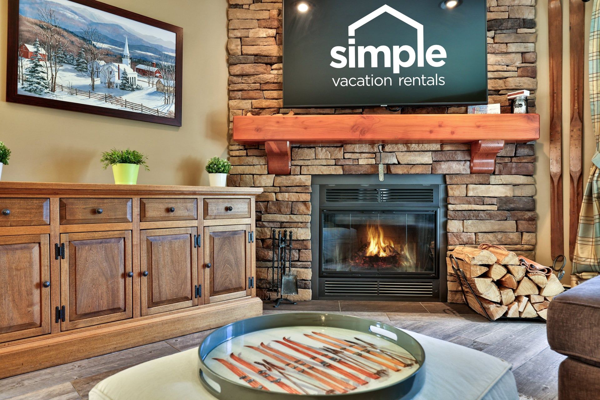 A cozy living room with a fireplace, wooden cabinets, and a sign for Simple Vacation Rentals.