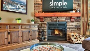 A cozy living room with a fireplace, wooden cabinets, and a sign for Simple Vacation Rentals.