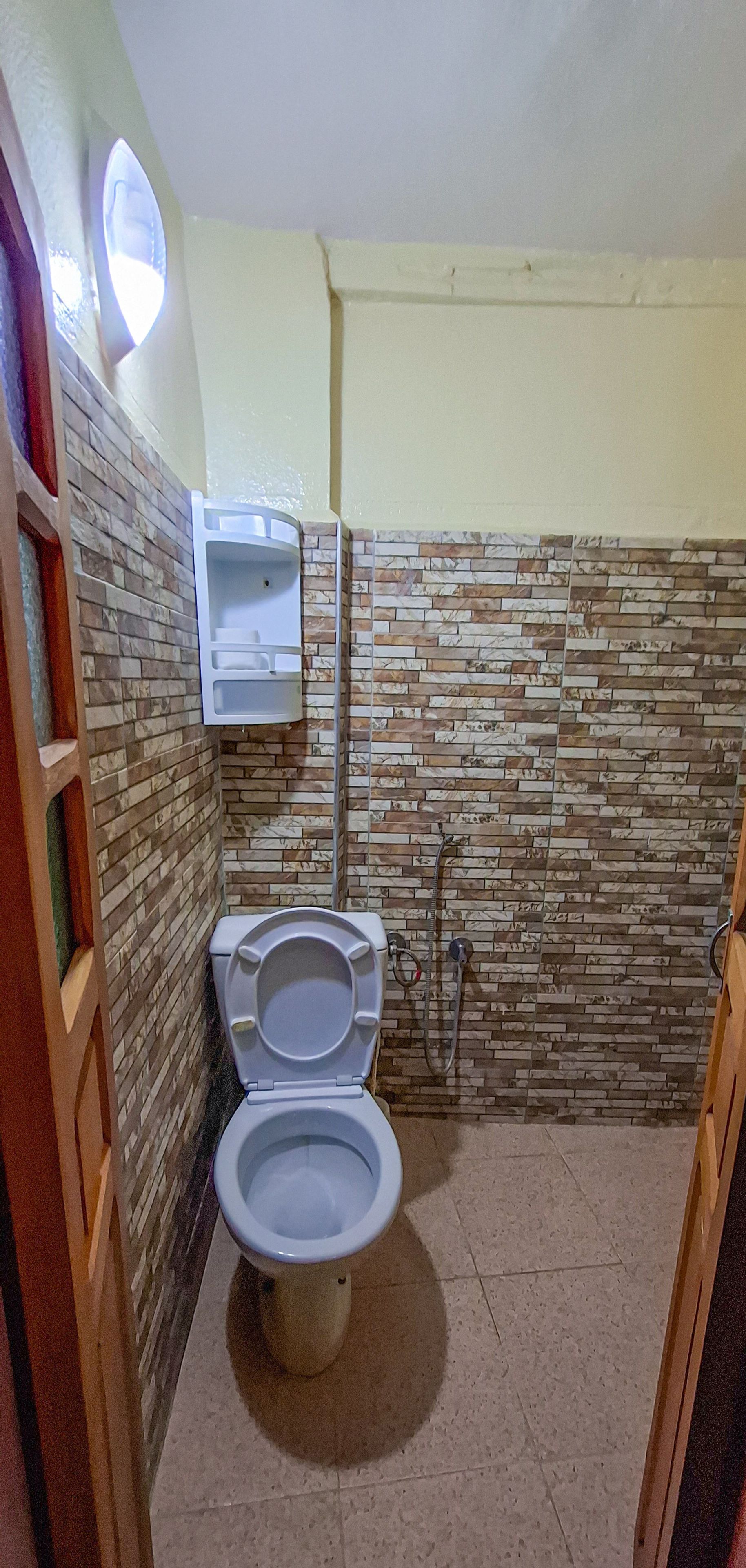Un baño pequeño con inodoro, lavamanos empotrado y ducha.
