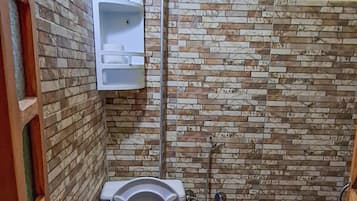 Un baño pequeño con inodoro, lavamanos empotrado y ducha.