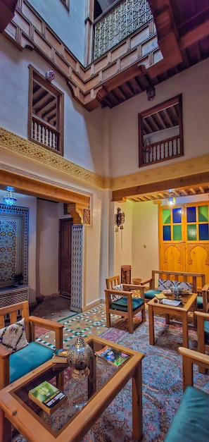 A traditional interior with wooden furniture, a patterned floor, and a balcony with decorative railings.
