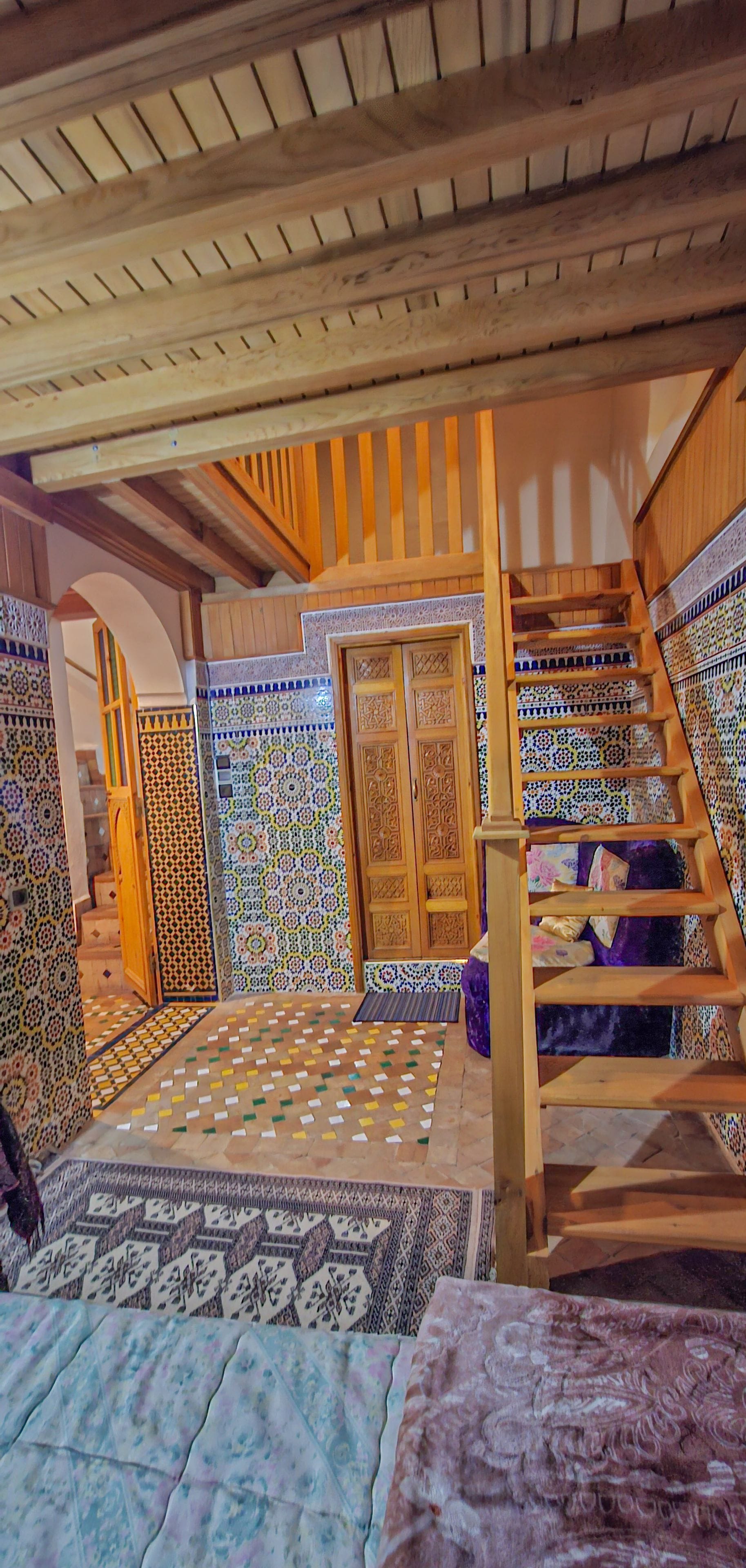 Une pièce dotée d’un escalier en bois, d’un parquet à motifs et d’une porte ornée de décorations complexes.