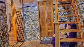 Une pièce dotée d’un escalier en bois, d’un parquet à motifs et d’une porte ornée de décorations complexes.