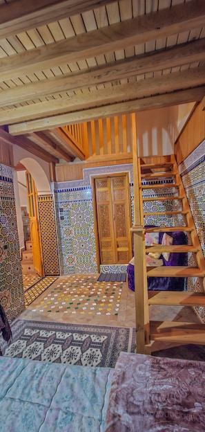 A room with a wooden staircase, a patterned floor, and a door with intricate designs.