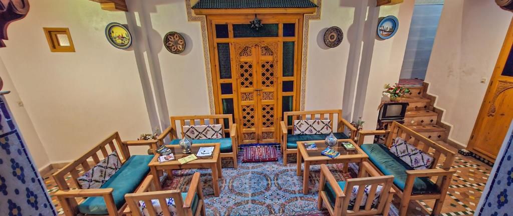 Quarto acolhedor com uma mesa de madeira central rodeada por cadeiras, um tapete estampado e uma porta de madeira decorativa.