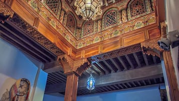 An ornate interior with a wooden ceiling, intricate carvings, and a hanging lantern.