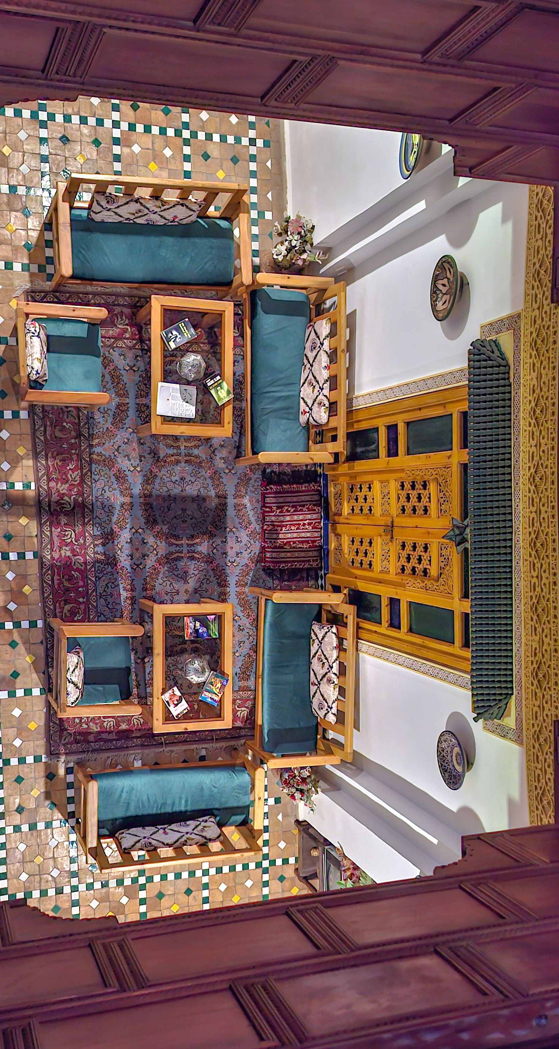 Quarto com área de estar central, piso estampado e parede decorativa.