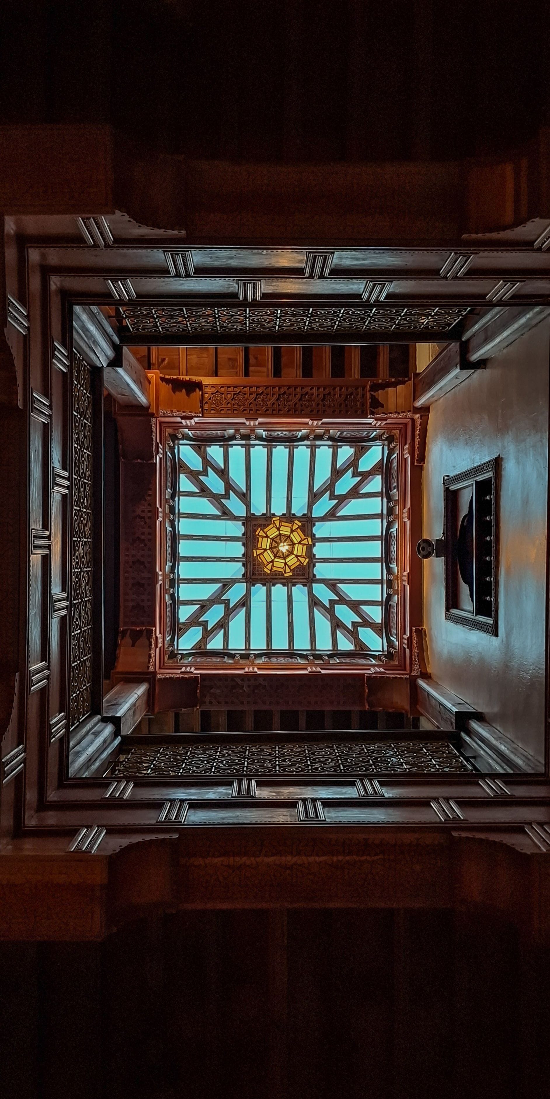 Quarto com uma janela grande e elaborada e um lustre central.