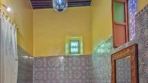 A room with two beds, a hanging light fixture, patterned walls, and a tiled floor. - Dar roeya (Fes)