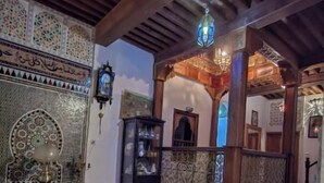 A traditional interior with a sofa, a patterned rug, and a wooden ceiling. - Dar roeya (Fes)