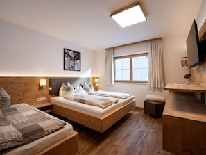 Ein Schlafzimmer mit einem großen Bett, Nachttischen, einem Fenster mit Vorhängen, einem Gemälde an der Wand und einem Holzboden.