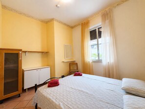 Ein Hotelzimmer mit einem Bett, einem Kleiderschrank, einem Sessel und einem fenster mit Vorhängen.