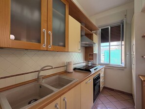 Eine Küche mit Holzausstattung, einer Spüle, einem Herd und einem Fenster.