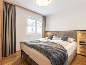A bedroom with a bed, curtains, a window, and a wooden headboard. - Holiday Apartment With 2 Bedrooms (Rauris)