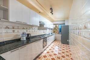 A modern kitchen with white cabinets, a black countertop, and a patterned floor. - Dar Raha House of Rest—a cozy vacation rental with a garden and terrace (Aourir)