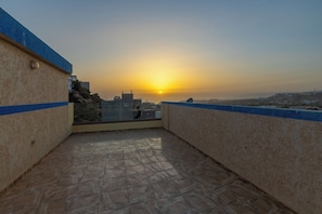 A rooftop terrace with a view of the sunset and distant buildings. - Dar Raha House of Rest—a cozy vacation rental with a garden and terrace (Aourir)