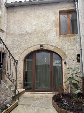 A building entrance with a stone facade, a wooden door, and a sign above the door. - L'Oustal Del Nort - Vacation Rental for 6 People Near Millau (Aveyron) (Paulhe)