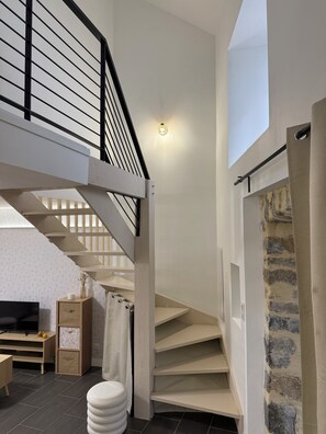 A modern interior with a staircase, a flat-screen TV, and a cozy seating area. - L'Oustal Del Nort - Vacation Rental for 6 People Near Millau (Aveyron) (Paulhe)