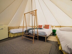 Een tent met twee bedden, een hangstoel en een kleine tafel.