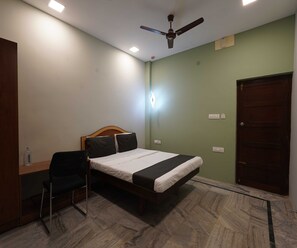 A bedroom with a bed, a desk, a chair, a ceiling fan, and a door. - Villa Tian by Palette Homes (Chennai)