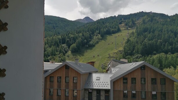 A view of a building with a sloped roof, multiple windows, and a wooden facade. - Vrbo Property (Saint-Chaffrey)