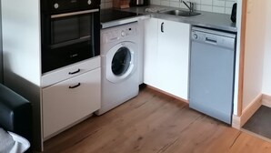 A compact kitchen with a microwave, oven, washing machine, and dishwasher. - Vrbo Property (Saint-Chaffrey)