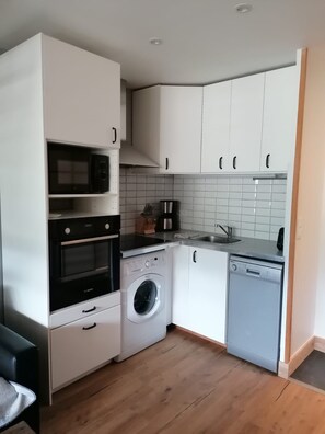 Une cuisine compacte équipée d’un four à micro-ondes, d’un four, d’un lave-linge et d’un lave-vaisselle.