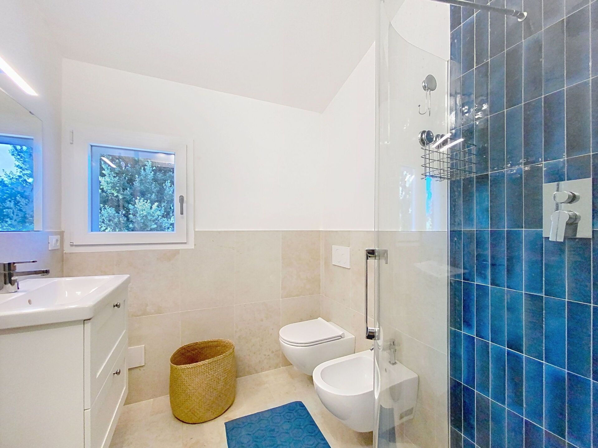 Une salle de bain moderne équipée de toilettes, d’un bidet et d’une douche séparée par des parois en verre.
