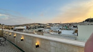 Terraço no terraço com vista para a paisagem urbana, incluindo edifícios e uma colina.
