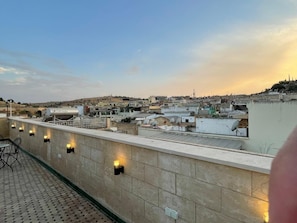 En takterrass med utsikt över en stadsbild, inklusive byggnader och en kulle.