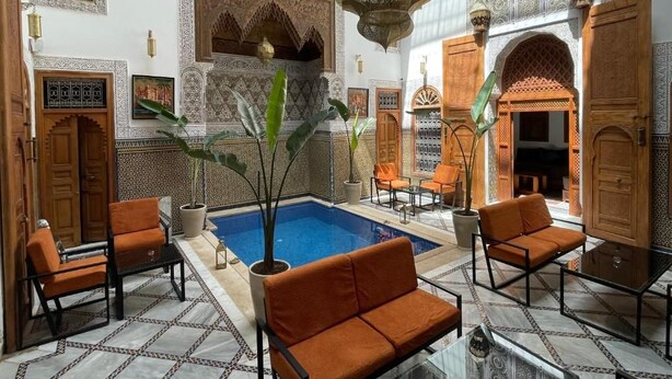 Interior tradicional marroquino com piscina, área de estar e decoração requintada.