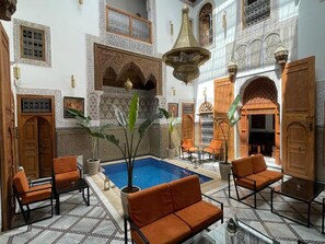 A traditional Moroccan interior with a pool, seating, and ornate decor. - best bedroom in the rIad (Fez)