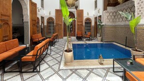 Piscina interna com mosaicos elaborados e áreas de estar.