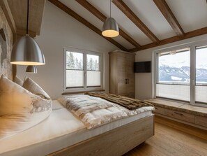 A bedroom with a bed, wooden beams, a window with a view, and a television. - Apartment in Mittersill With Swimming Pool (Mittersill)